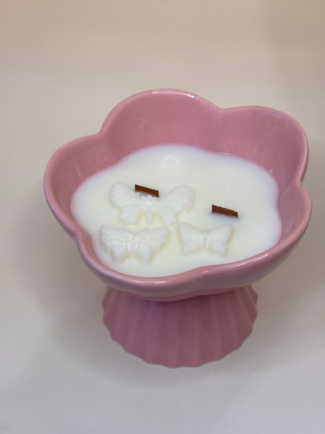 Vela de duas mechas com borboletas em relevo num vaso rosa em forma de flor